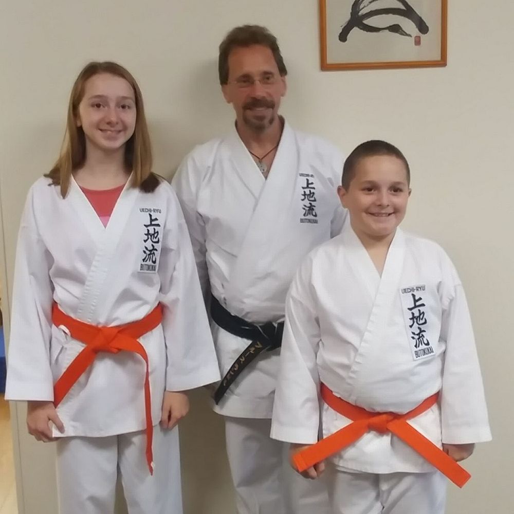 Randall School of Karate - Sensei Bruce Randall, Head Master of Randall School of Karate in Exeter with Maddie and Collin Hardy after they received their Orange belts. - Karate Near Me - Exeter, New Hampshire Randall School of Karate - Sensei Bruce Randall, Head Master of Randall School of Karate in Exeter with Maddie and Collin Hardy after they received their Orange belts. - Karate Near Me - Exeter, New Hampshire