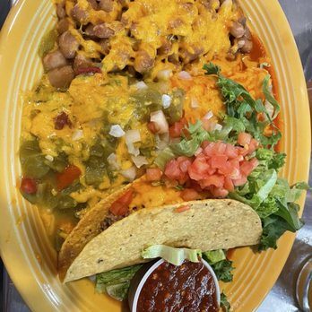 Duran Central Pharmacy - Combo plate Christmas style - The image shows a yellow oval plate containing a Mexican-style meal. It includes beans topped with melted cheese, rice mixed with vegetables, a taco with lettuce and diced tomato, and a small cup of salsa. The meal features typical ingredients such as beans, rice, lettuce, tomato, and salsa, presented in a colorful and appetizing manner. - Mexican Near Me - Albuquerque, New Mexico