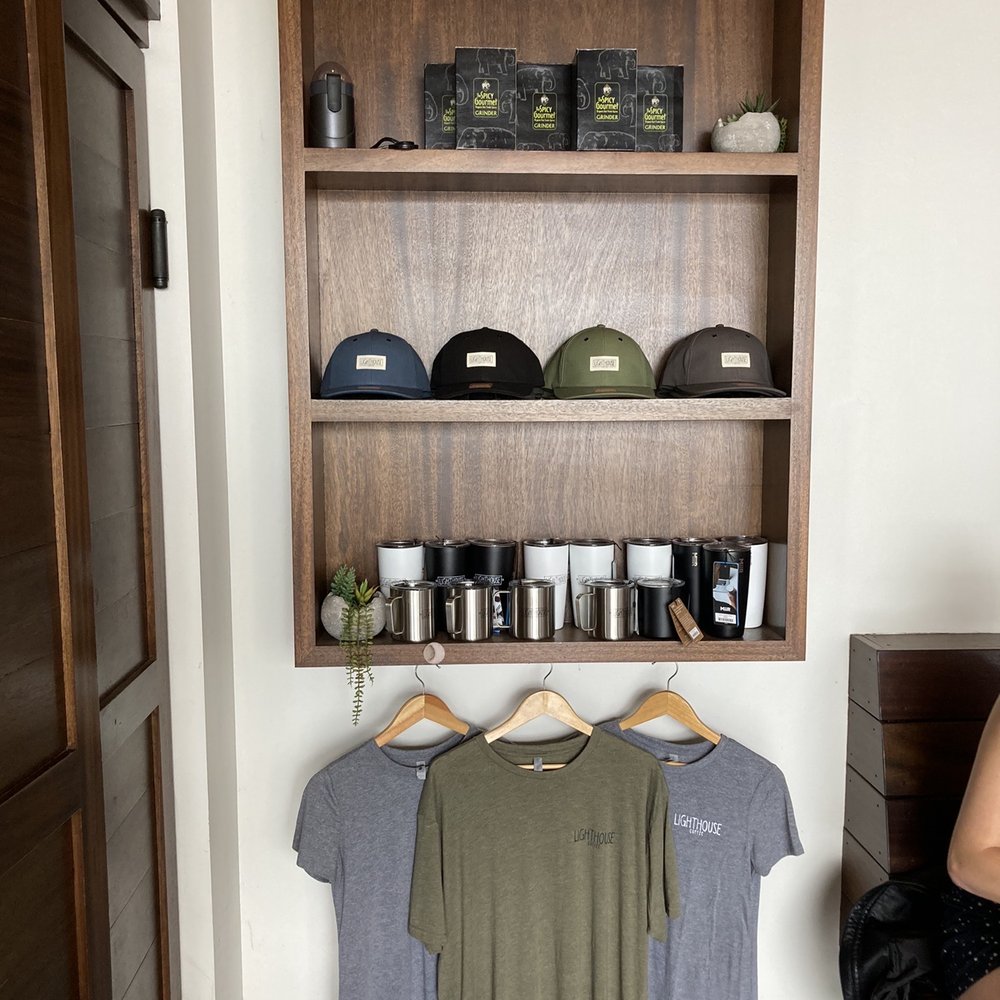 Lighthouse Coffee - a shelf of coffee and t - shirts - Coffee & Tea Near Me - Santa Barbara, California Lighthouse Coffee - a shelf of coffee and t - shirts - Coffee & Tea Near Me - Santa Barbara, California