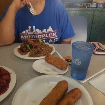 New China - a woman sitting at a table with plates of food - Chinese Near Me - Windsor, Missouri