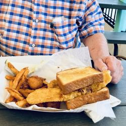 Skipper's River Cafe and Steamboat Marina - Generous fish sandwich platter includes savory fried, hush puppies, and coleslaw with a side of tartar sauce.