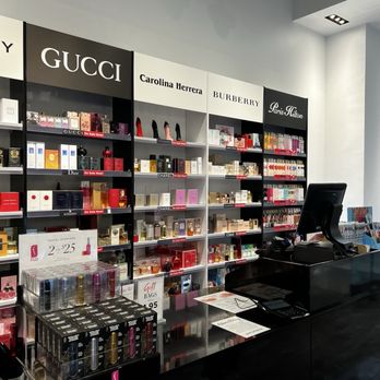 Perfumania - A perfume store interior featuring shelves with designer brands like Gucci, Carolina Herrera, Burberry, and Paris Hilton, with perfume bottles and promotional signs. - Perfume Near Me - Paramus, New Jersey