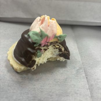 Bake - Yummy goodness - A partially eaten cookie decorated with pink and green floral icing and coated with chocolate, placed on a gray surface. - Bakeries Near Me - Summit, New Jersey
