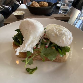 Stella San Jac - Avocado toast with poached egg and biscuits in the background - New American Near Me - Austin, Texas Stella San Jac - Avocado toast with poached egg and biscuits in the background - New American Near Me - Austin, Texas