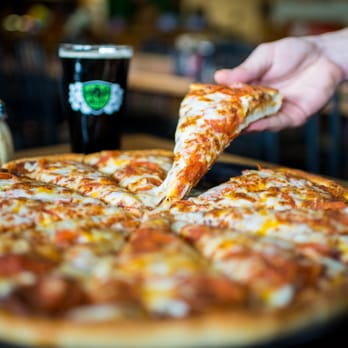 Abby's Legendary Pizza - a hand holding a slice of pizza - Pizza Near Me - Grants Pass, Oregon