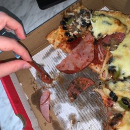 a person cutting a slice of pizza
