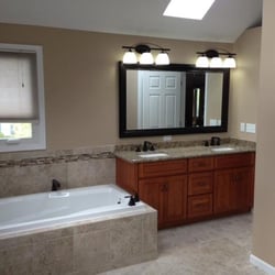 Jenkins Contracting - This angle view shows the generous tub with a remote spout location and a new vanity, quartz top and new faucets in Delta oil...