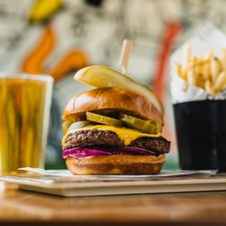 Flanker Kitchen + Sports Bar - Backyard Burger made with griddled 8oz Black Angus patty, American cheese, dill pickles and sweet onion