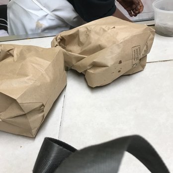 Da Place Cuisine - a person sitting at a table with two bags of food - Caribbean Near Me - Brooklyn, New York