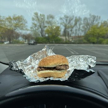Five Guys - a hamburger on tin foil on the dashboard of a car - Burgers Near Me - Latham, New York