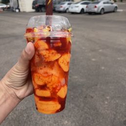 a hand holding a plastic cup with a drink in it a hand holding a plastic cup with a drink in it