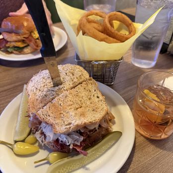 Tonys Grill & Bar - Pastrami Ruben with onion rings - Cocktail Bars Near Me - Palm Springs, California Tonys Grill & Bar - Pastrami Ruben with onion rings - Cocktail Bars Near Me - Palm Springs, California