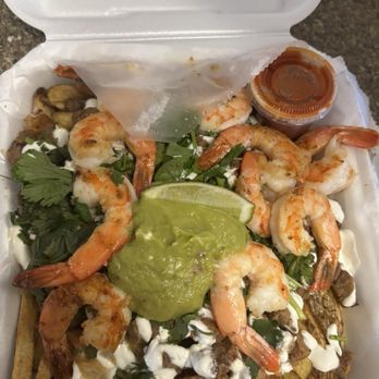 La Vaquerita - Asada Shrimp Fries - A takeout container holds shrimp fries garnished with guacamole, sour cream, cilantro, and a side of sauce, with visible fries and shrimp. - Food Trucks Near Me - El Paso, Texas