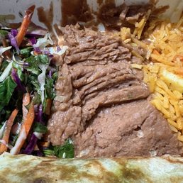 Spinach salad, Beans, rice.   delicious. - A close-up image showing shredded beef, seasoned rice, and a mixed vegetable salad with carrots, cabbage, and greens.