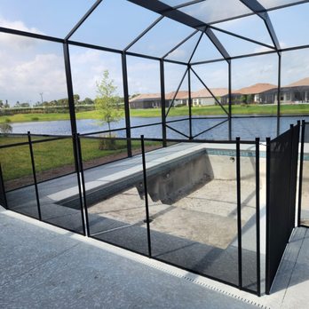 The Pool Fence Company - 4' black mesh pool fence with 90° turn, installed around an empty pool inside a screened enclosure with a scenic lake view in the background - Fences & Gates Near Me The Pool Fence Company - 4' black mesh pool fence with 90° turn, installed around an empty pool inside a screened enclosure with a scenic lake view in the background - Fences & Gates Near Me
