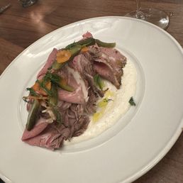 Prime rib salad - A dish featuring sliced prime rib with green beans and carrots, served on a bed of mashed potatoes with gravy, on a white plate.