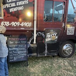 a woman standing next to a food truck a woman standing next to a food truck