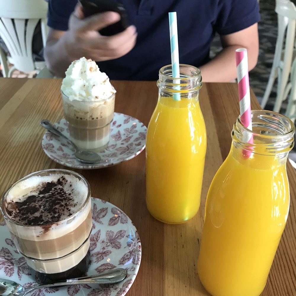 Coffee (bombon in the back, mochaccino in the front) and orange juices Coffee (bombon in the back, mochaccino in the front) and orange juices