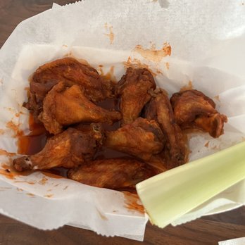 Chicken Licks - Buffalo wings - Buffalo chicken wings served in a paper-lined basket, with a celery stalk on the side, likely from a casual restaurant or bar. - Chicken Wings Near Me - Sun Prairie, Wisconsin