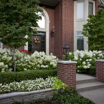 Twin Pines Landscaping - Welcome to an enchanting home entrance featuring a landscaped walkway, beautiful hydrangeas, trees, and white flowers. - Landscaping Near Me - Troy, Michigan Twin Pines Landscaping - Welcome to an enchanting home entrance featuring a landscaped walkway, beautiful hydrangeas, trees, and white flowers. - Landscaping Near Me - Troy, Michigan