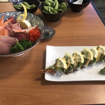 Sushibucks - A plate of sushi rolls topped with lemon slices and a side of wasabi, along with a sashimi bowl containing various raw fish and garnishes, on a wooden table. - Japanese Near Me - Albuquerque, New Mexico