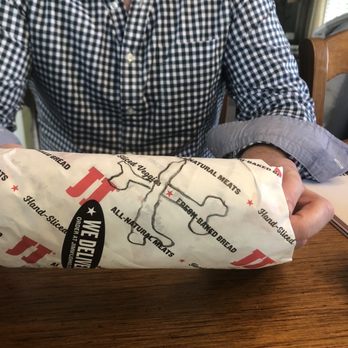 Jimmy John's - a man sitting at a table with a sandwich in his hand - Sandwiches Near Me - Rockford, Michigan