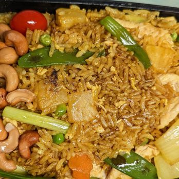 Eggs & Thai Café - Pineapple fried rice (flavorful) - A serving of pineapple fried rice with vegetables, cashews, and pineapple chunks in a black takeout container. - Thai Near Me - Dedham, Massachusetts