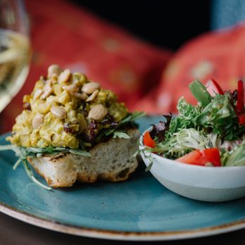 Table 128 - chicken salad tartine | 
yellow curry, roasted chicken, celery, cranberries, argula, marcona almonds, toasted focaccia, choice of side - New American Near Me - Des Moines, Iowa