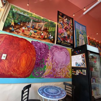 Manitas Cafe - a table and chairs in front of a mural - Salvadoran Near Me - San Francisco, California Manitas Cafe - a table and chairs in front of a mural - Salvadoran Near Me - San Francisco, California