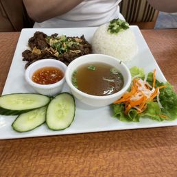 Grilled beef and rice with cup of soup broth and pickled vegetables.