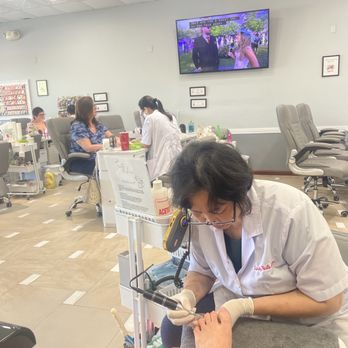 Trinity Nails & Spa - Nice job! - A healthcare professional is treating a patient's foot in a clinical setting, with other patients and a television visible in the background. - Nail Salons Near Me - Peoria, Arizona
