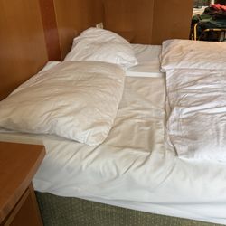 Hoteltraube Rüdesheim - Hotel bed, showing thin sheets and worn / stained bedskirt.