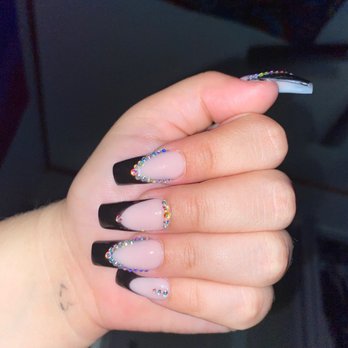 Nail Tech - this is what i received - A hand with acrylic nails displays a French manicure style with black tips and rhinestone embellishments, set against a dark background. - Nail Salons Near Me - Oroville, California