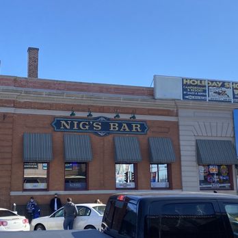 Nig's Bar - cars parked in front of the building - Facade of Nig's Bar in Wisconsin Dells, featuring a sign, windows with striped awnings, and people outside, with parked cars in front. - Bars Near Me - Wisconsin Dells, Wisconsin