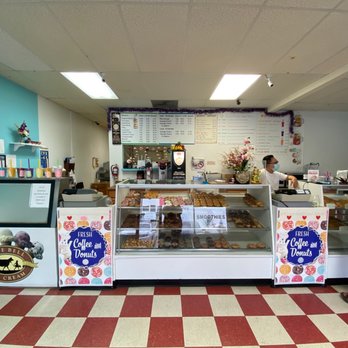 Donut Palace - a man standing in front of a display of donuts - Donuts Near Me - Pflugerville, Texas