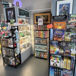 Starbase 505 - Kids game shelf, puzzle shelves, and some trading cards and action figures in the case.