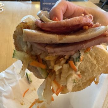 Lan Viet - Traditional Banh Mi - A person holds a Vietnamese banh mi sandwich filled with pork, pickled vegetables, and herbs, with a bread roll on top. - Vietnamese Near Me - Dublin, Ohio