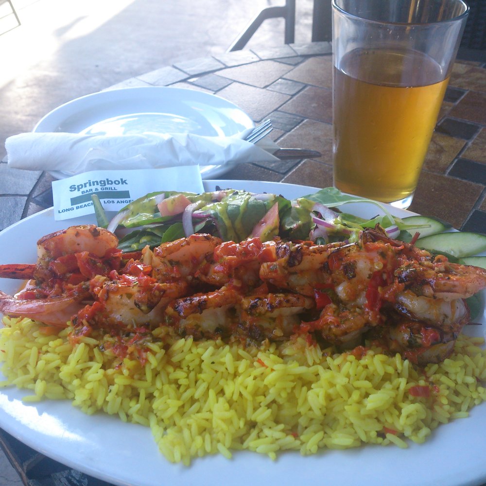 Springbok Bar & Grill - Pete's Pili Pili Prawn: grilled w/ lightly spicy tomato/red bellpepper sauce, buttery tumeric rice, salad w/ mustard vinaigrette - Sports Bars Near Me - Van Nuys, California Springbok Bar & Grill - Pete's Pili Pili Prawn: grilled w/ lightly spicy tomato/red bellpepper sauce, buttery tumeric rice, salad w/ mustard vinaigrette - Sports Bars Near Me - Van Nuys, California