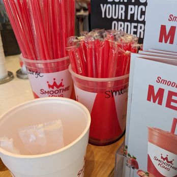 Smoothie King - Size reference - Red straws in two plastic containers at Smoothie King, with signage and promotional materials nearby. - Juice Bars & Smoothies Near Me - Gilbert, Arizona