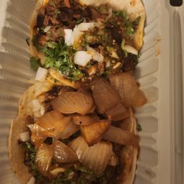 Two al pastor tacos adorned with half-dollar sized chunks of onion Two al pastor tacos adorned with half-dollar sized chunks of onion