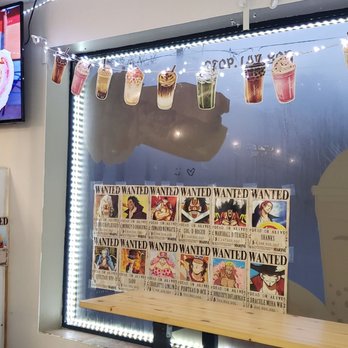 BB Tea - Anime posters & artsy bubble tea banner! - String of colorful drink posters hangs above a window in a cafe or bubble tea shop, with LED lighting and a wanted poster display below. - Bubble Tea Near Me - South Plainfield, New Jersey