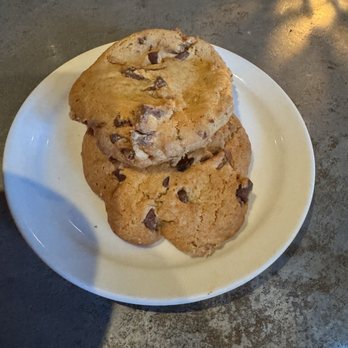 The Devilbiss Room - Special order chocolate chips cookies.  Yum!!!! - A white plate holds three chocolate chip cookies stacked on top of each other. The cookies are golden brown with visible chocolate chips. The plate is on a dark, textured surface, possibly a table, with some reflections and shadows visible around it. - Lounges Near Me - Winters, California