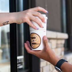 Ziggi's Coffee - Hands passing a hot Ziggi's Coffee cup through a drive-thru window.