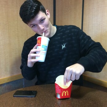 McDonald's - a man sitting at a table drinking from a cup - Fast Food Near Me - Maple Ridge, British Columbia