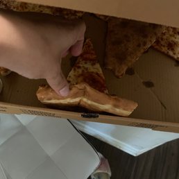 a hand reaching for a slice of pizza