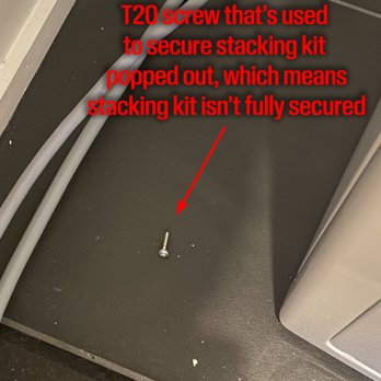YF Logistics - Photo is self explanatory. - A metal screw is placed on a dark, textured floor surface near electrical cables and a piece of equipment. Red text overlay explains that the screw is used to secure a stacking kit but is not fully secured, indicating a potential safety concern or incomplete installation. - Shipping Centers Near Me - Cranbury, New Jersey