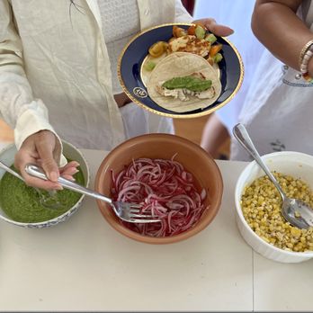 Capt. Tom's Charters - Two people are seen serving themselves food from a variety of dishes on a table, including salads, sauces, and cooked items. The table features bowls of sliced onions, corn salad, and other side dishes, with plates of food being prepared for serving. - Fishing Near Me - Nantucket, Massachusetts