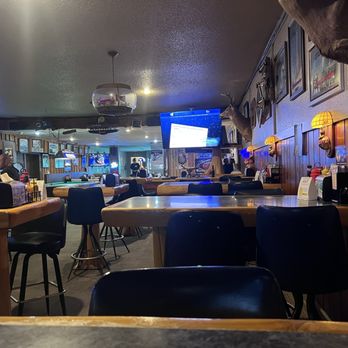 Rapid River Pub - A bar interior featuring wooden paneling, mounted animal heads, wall-mounted lamps, and multiple television screens. - Pubs Near Me - Rapid River, Michigan
