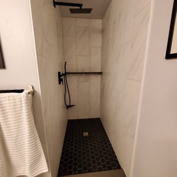 Set In Stone - a walk - in shower with black and white tile - General Contractors Near Me