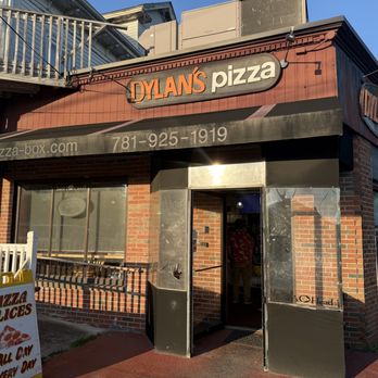 Dylan’s Pizza - Directly across from the Hull DPW and 60 seconds away from the peaceful Weir river. - The image shows the storefront of Dylan's Pizza, featuring signage, a brick exterior, and an outdoor pizza menu board. - Pizza Near Me - Hull, Massachusetts